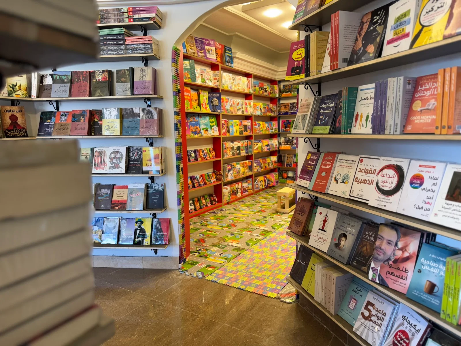 رفوف المكتبة والقوس المؤدي إلى قسم كتب الأطفال